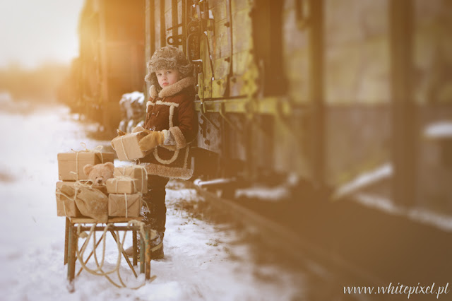 Chłopiec ładuje prezenty świąteczne zimowez sanek na wagon pociągu