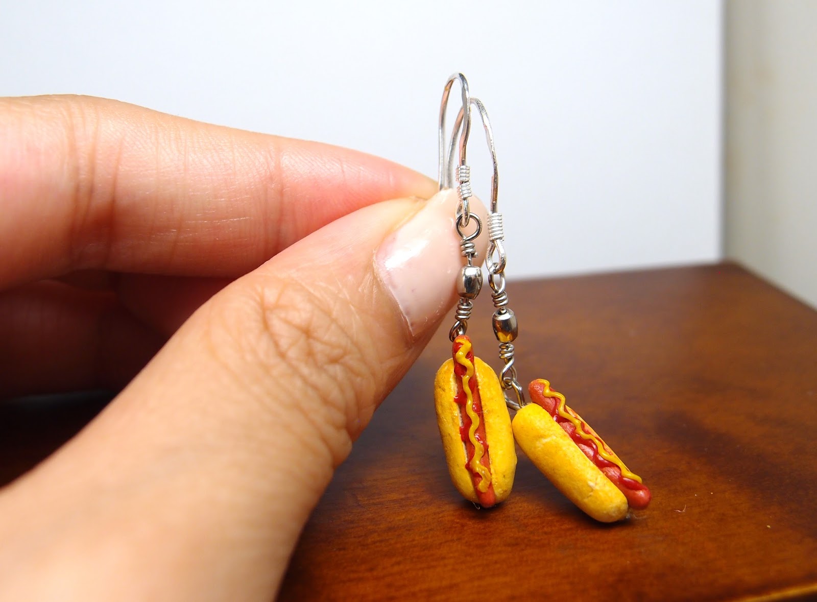 two hot dogs with tomato sauce and ketchup on a sterling silver earring post.