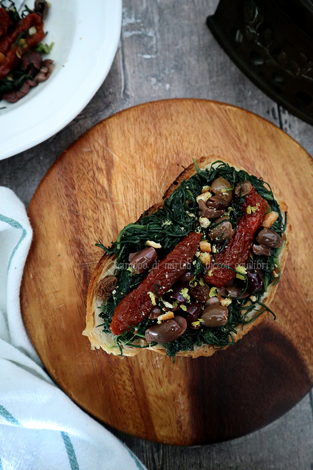 Bruschetta con agretti, olive, pomodori secchi, uvetta e briciole