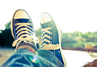 Feet in sneakers relaxing by lake