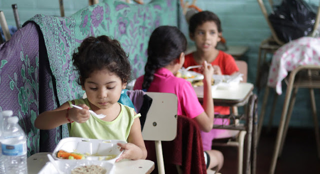 Estas niñas salvadoreñas eran beneficiarias de los almuerzos escolares. Ahora esas raciones de alimentos se preparan  para que los niños se los lleven a sus casas. PMA/David Fernandez