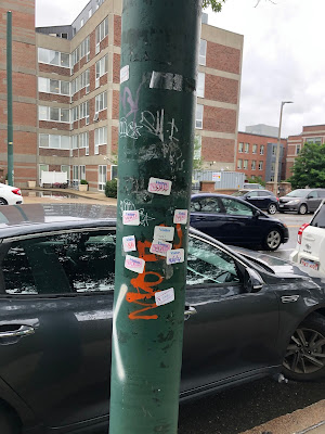 Another pole covered with a smattering "Visitor/Void" stickers, taken August 5, 2021