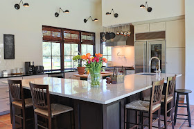 white granite countertops, blanco montana granite, open kitchen plan, glass door refrigerator, wolf stove, white subway tile backsplash, hanging pot rack, kitchen windows at countertop height, proline range hoods, proline pro v range hood, proline hood, pot filler