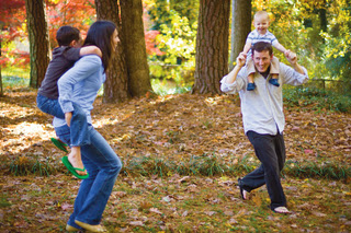 A mother and father play with their children outside