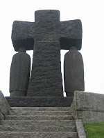 La grande croce di lava di basalto con la raffigurazione, di spalle, della madre e del padre