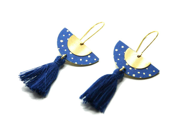 pair of polka-dot half-moon dangling earrings and a half-moon-shaped gold disc with blue thread tassels at the top