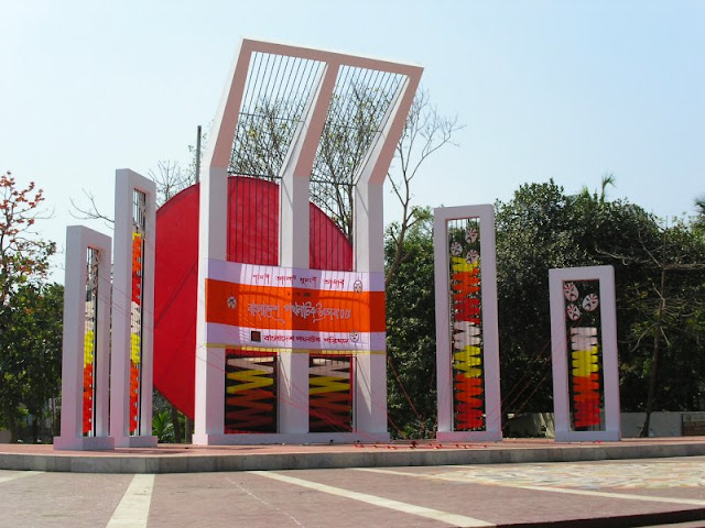 Monument consisting of five white rectangle frames, the largest in the middle, with Bangla writing displayed on it on a banner