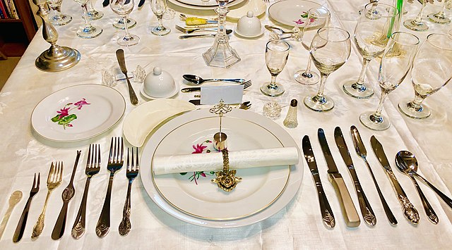 An elborate formal place setting with many utensils and wine glasses