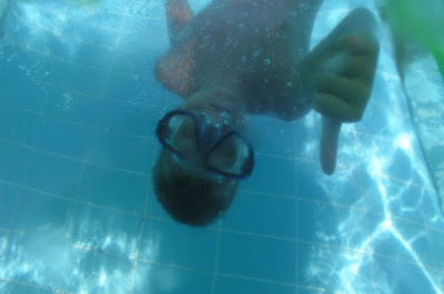 picture of a child in a underwater facemask, upsidedown in the pool giving a thumbs up. There are Therapeutic Benefits of Swimming