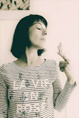 woman in striped shirt balancing a tiny dog figure on index finger and looking at it