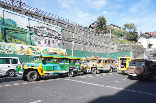 Multi-colored jeepneys pass by the national road