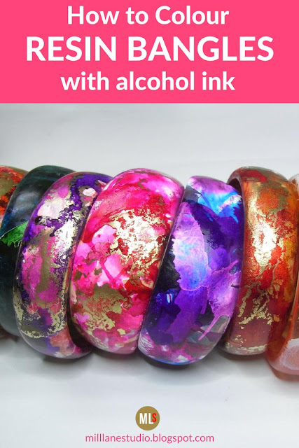 Row of brightly coloured alcohol ink bangles in shades of pink, red, purple, orange and green.