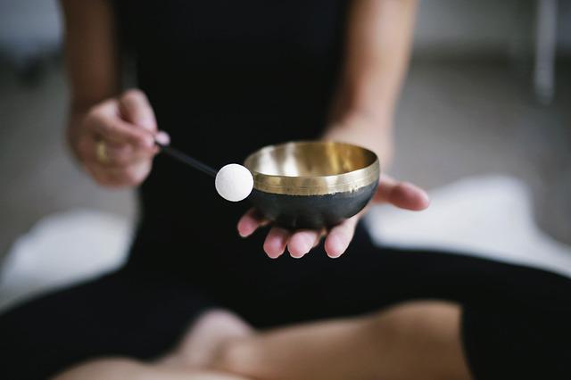 A lady in a black t-shirt is ringing a singing bowl. She spread spirituality.