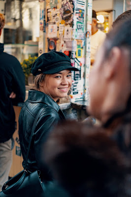 A woman wearing a cap smiling in a marketplace