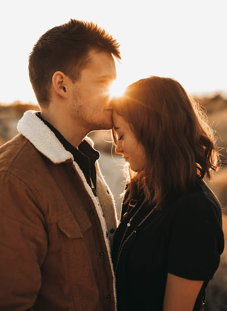 A man kissing a girl in the forehead.