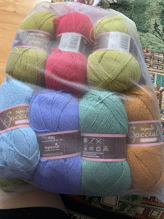 7 100g balls of yarn in various colors: moss green, dark pink, light moss green, light blue, blue-purple, light forest green, rust.