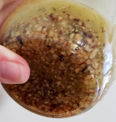 Bottom of mason jar filled with salad dressing, garlic, spices