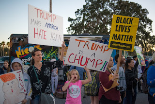 Protesters hold signs during the Trump visit to USF Tampa, FL.