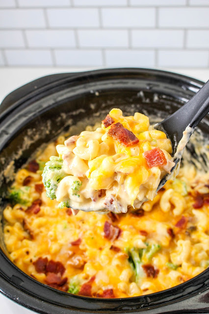 scoop of mac and cheese with slow cooker in the background.