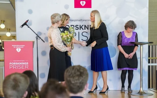 Crown Princess Mette-Marit wore a black jacket and a blue pleated skirt. Kristina Hermann Haugaa and Professor Ingvild Tina Saltvedt