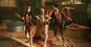 Two calico humanoid CG cats walk astride white humanoid CG cat Victoria, who is wearing a pearl necklace, beads roughly half the size of her head. They are all linking arms as they rob a human house.