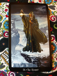 The Hermit -IX card. Old man in brown robes on a cold mountain, holding up a lantern