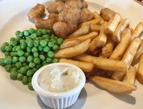 white plate with scampi, garden peas, chips and tartae sauce 