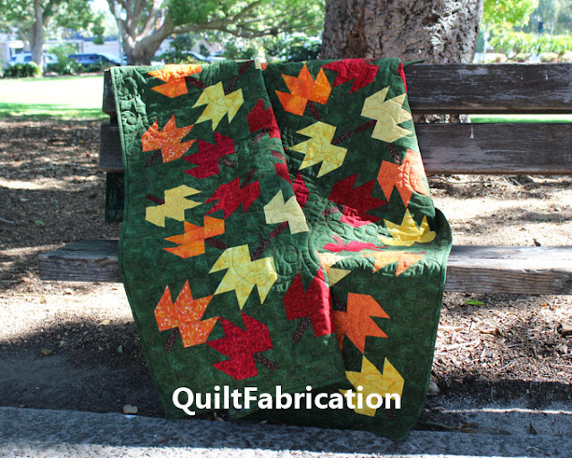 a quilt with fall leaves on a green background