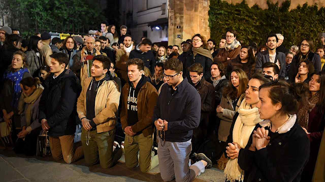 Jovens rezando ante Notre Dame incendiada