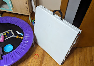 Folding table leaning on wall next to small trampoline
