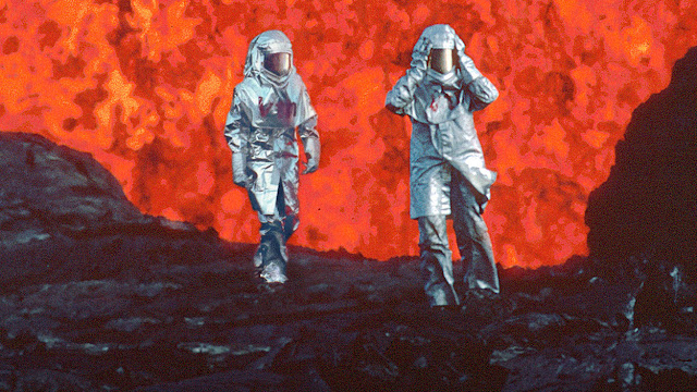 two people walking by lava in silver suits