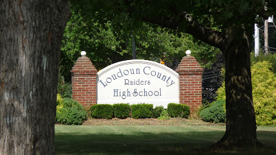 A school sign, surrounded by greenery and trees. The sign reads "Loudoun County High School" and "Raiders"