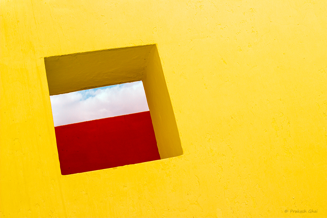 A Minimalist Photo of Yellow wall with a sqaure opening