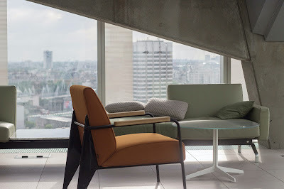 Concrete interior with angled window and midcentury curvy furniture