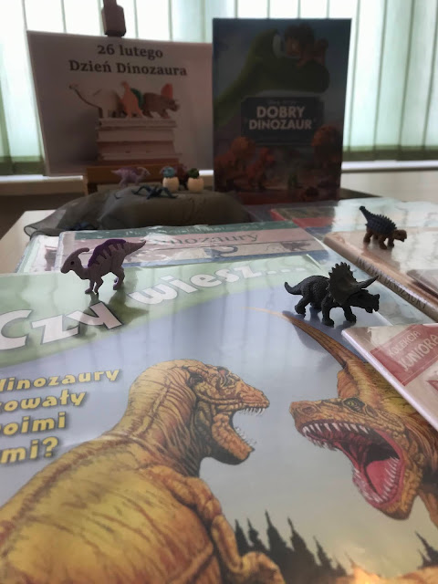 Na zdjęciu wystawka książkowa. Widać napis: 26 lutego Dzień Dinozaura, książki o „gadziej” tematyce oraz figurki dinozaurów