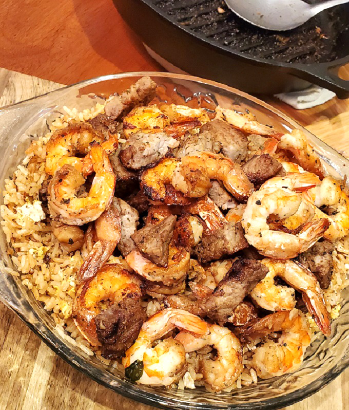 steak and shrimp hibachi style stir fried in a glass dish with fried rice