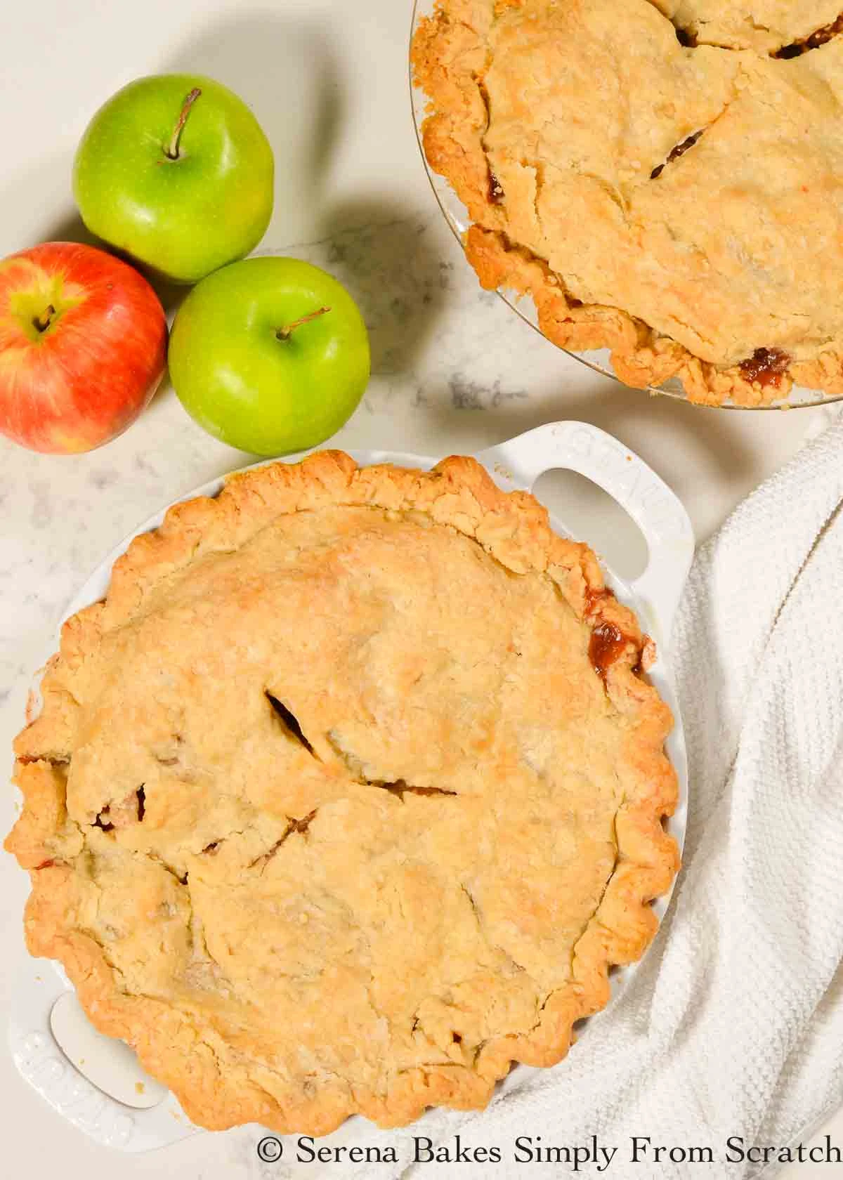 A down shot if 2 Apple Pies on a white marble cutting board.