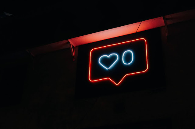 a text bubble with a heart inside in neon lights in a completely black background