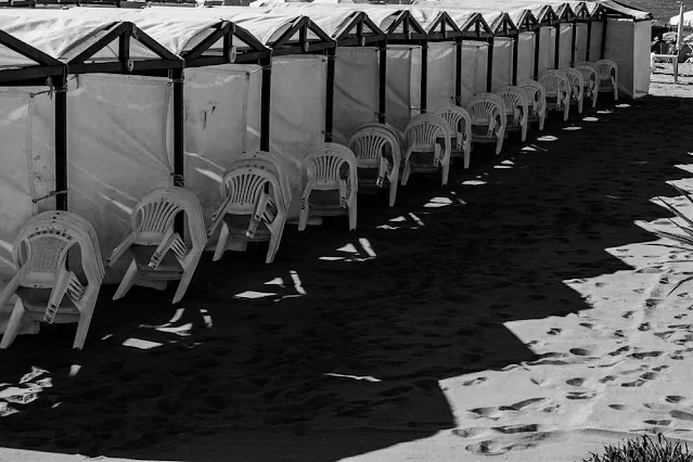 Sillas amontonadas a la sombra de las carpas de la playa.