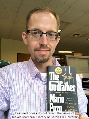 Adam holding a copy of The Godfather novel