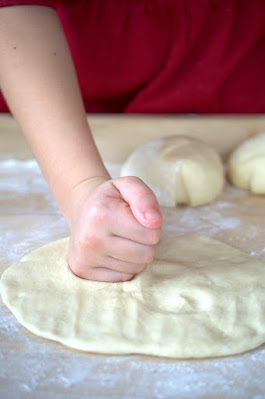 Ein Kind formt mit seinen Händen einen Thomaswecken.