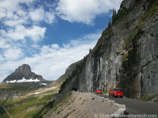 These red, old-timey tour buses are heading west up the Going-to-the-Sun Road, approaching the top of Logan Pass, at Glacier National Park, Montana.