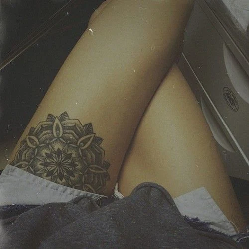 chica sentada con piernas cruzdas en un coche, con tatuaje de mandala en la pierna izquierda