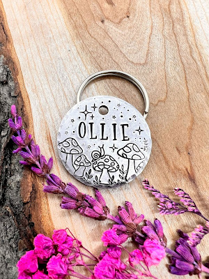 A silver-coloured dog tag with Ollie on it and a set of mushrooms