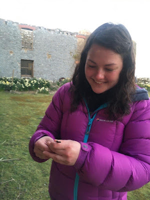 A woman with a large smile on her face holding a very small slow worm