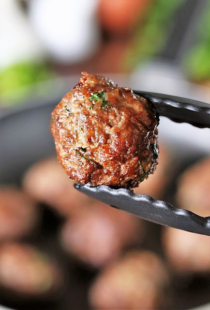 Tongs Holding Browned Homemade Meatball Image