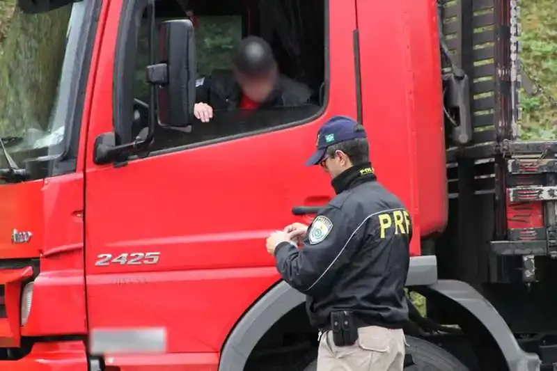 Agente da PRF abordando caminhão vermelho