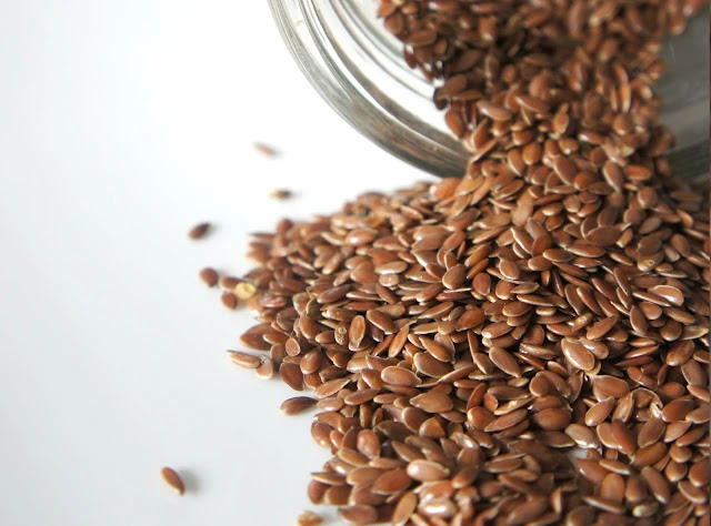 poring flax seeds from a transparent glass container