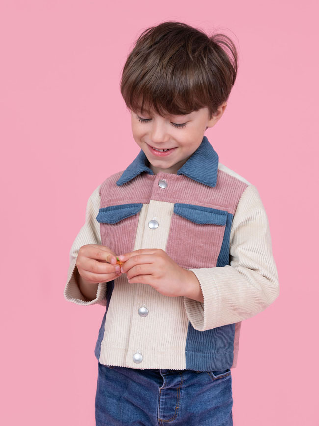 Boy wears colour block corduroy jacket in pink, blue and cream