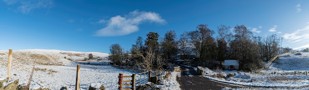 Panorama of trees and hillsides in the snow, old building in the trees